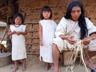 Ein junger Kogi stellt einen Basthut her, im Hintergrund zwei Kinder