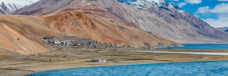 Salzsee mit vereinzelten Häuser vor einem Bergpanorama