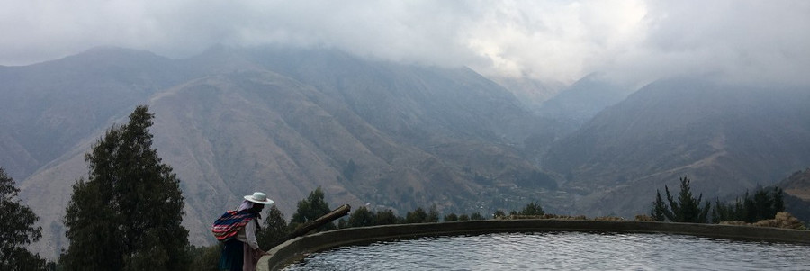 Zwei Personen stehen an einem Wasserbecken vor dem Panorama der Anden