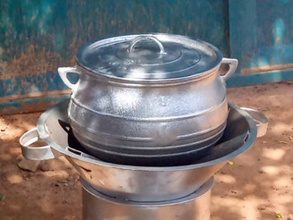 Auf einem Nafagaz-Kocher der mit Holz geheizt wird, steht ein Topf in dem gekocht wird