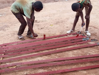 Arbeiter bemalen Zaun mit roter Farbe in Burkina Faos