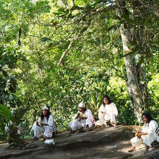 Männer des indigenen Volk der Kogi sitzen auf einem Stein im dichten Regenwald in Kolumbien