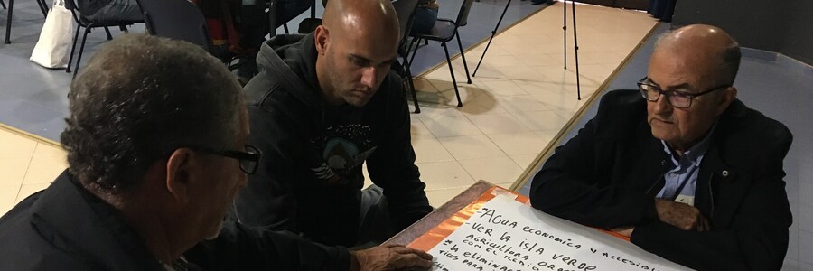 Personen sitzen an Tisch mit Schreibutensilien Personen sitzen an Tisch mit Schreibutensilien