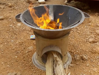 Holz steckt in einem Kocher und brennt, wodurch Holzkohle hergestellt wird