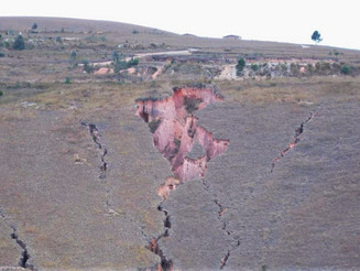 Tiefe Risse im Boden zeigen sich an einem Hang auf Madagaskar aufgrund von Brandrodung und Erosion