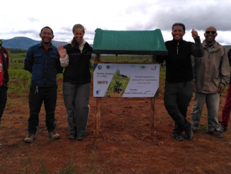 Katja Wiese, die Geschäftsführerin von Naturefund, steht mit Projektpartner neben Schild vor DAF-Parzelle in Ibity auf Madagaskar