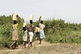 Frauen und Kinder tragen Körbe auf ihrem Köpfen in Burkina Faso