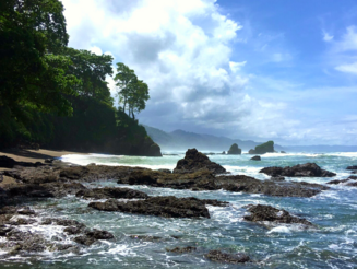 Tropische Küste mit Felsen, tiefblauem Wasser, Sandstrand und Palmen