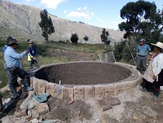 Männer bauen ein rundes Wasserbecken in den Bergen