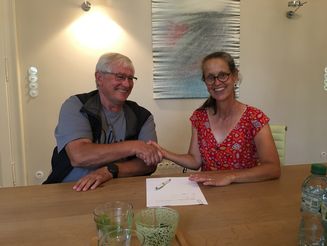 Katja Wiese, Geschäftsführerin von Naturefund, und ein Eigentümer eines Grundstückes sitzen an einem Tisch und schütteln sich die Hand