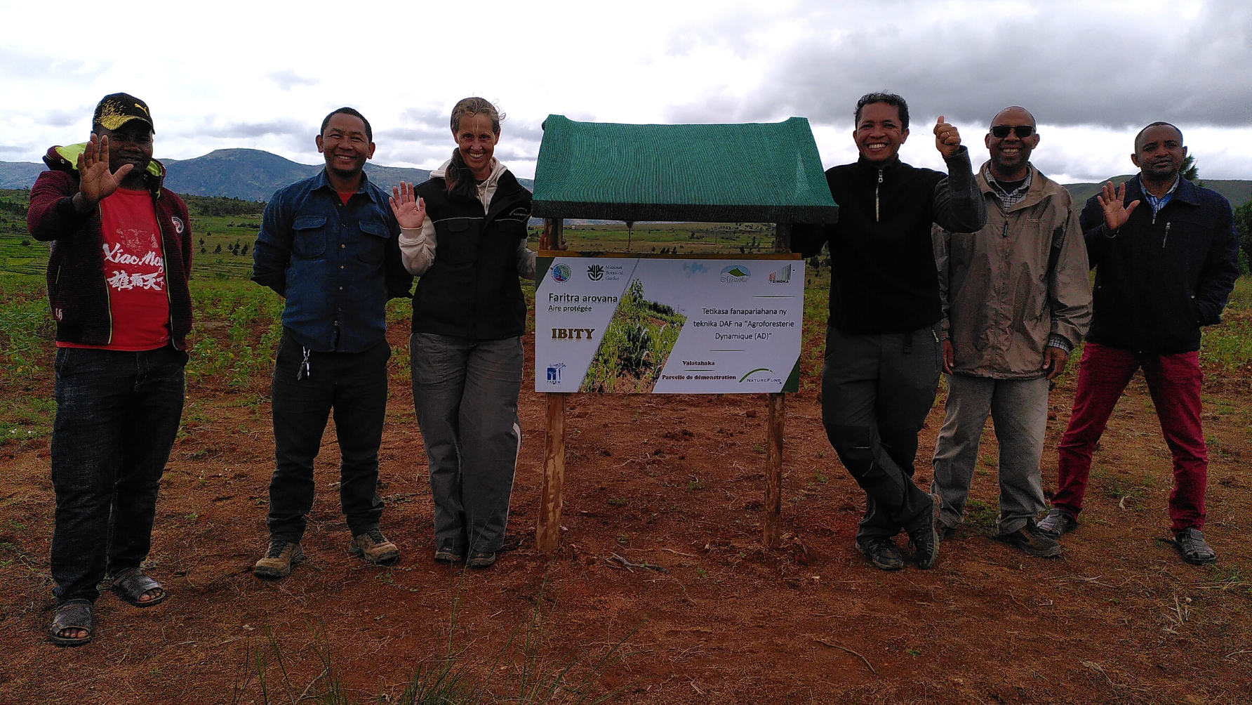 Katja Wiese, die Geschäftsführerin von Naturefund, steht mit Projektpartner neben Schild vor DAF-Parzelle in Ibity auf Madagaskar